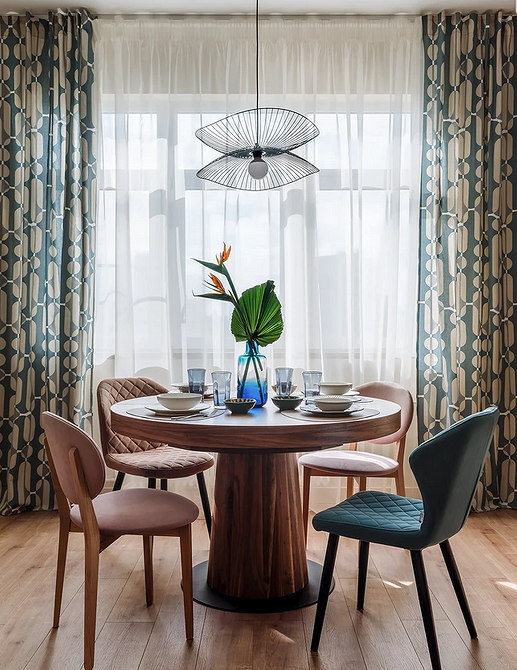 Дизайн інтер'єру з круглим обіднім столом та м'якими стільцями для комфортного відпочинку.