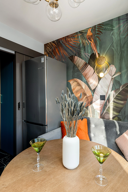 Інтер'єр кухні з дерев'яним круглим столом та м'якими стільцями в обідній зоні.