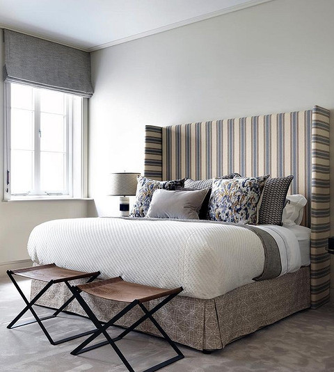 Розкішний дизайн спальні з ліжком з об'ємним м'яким узголів'ям та декоративними подушками.