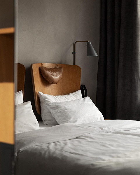 Інтер'єр спальні з ліжком з шкіряним узголів'ям коричневого кольору та елегантними світильниками.