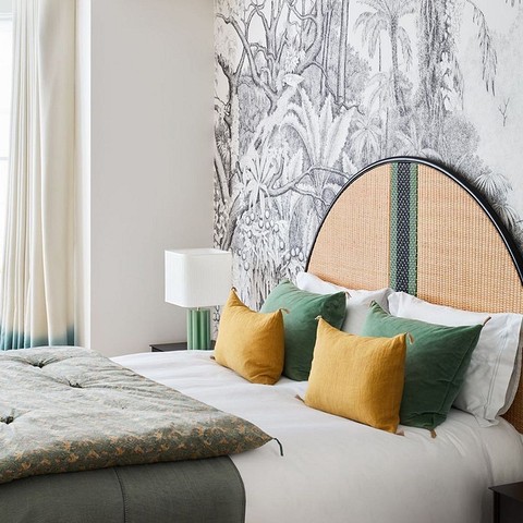 Стильна спальня з ліжком з тканинним узголів'ям з геометричним візерунком та декоративним текстилем.