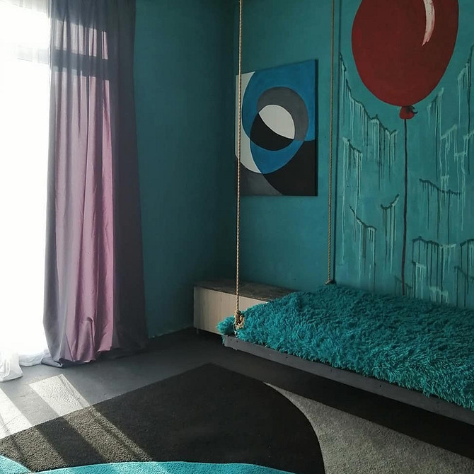 Простора спальня з великим підвісним ліжком та панорамними вікнами, наповнена світлом.