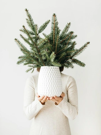 Різдвяний декор з хвої: свічки та ялинкові гілки на каміні.