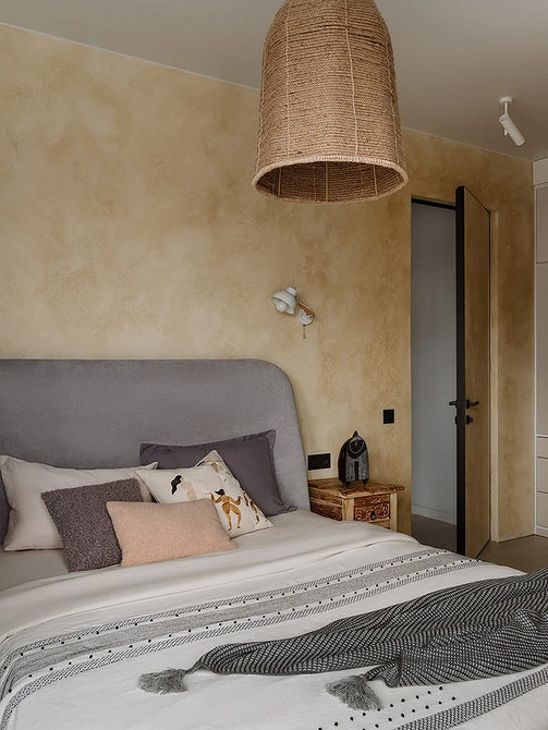 Інтер'єр спальні з сірим ліжком, дерев'яними тумбочками та теплим освітленням.