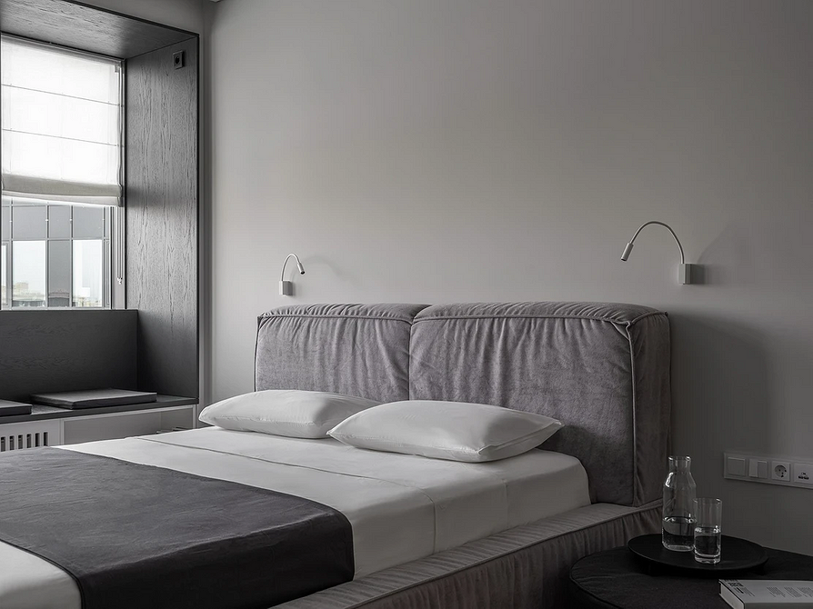 Елегантна сіра спальня з м'яким ліжком, приліжкові тумбочки та сучасний декор.