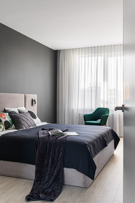 Інтер'єр спальні в сірих тонах з м'яким сірим ліжком та дерев'яними елементами.