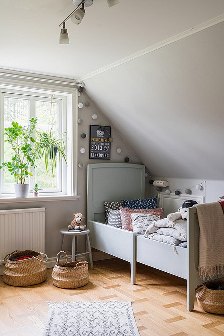 Сіра ліжко з м'яким узголів'ям в сучасній спальні з дерев'яними меблями.