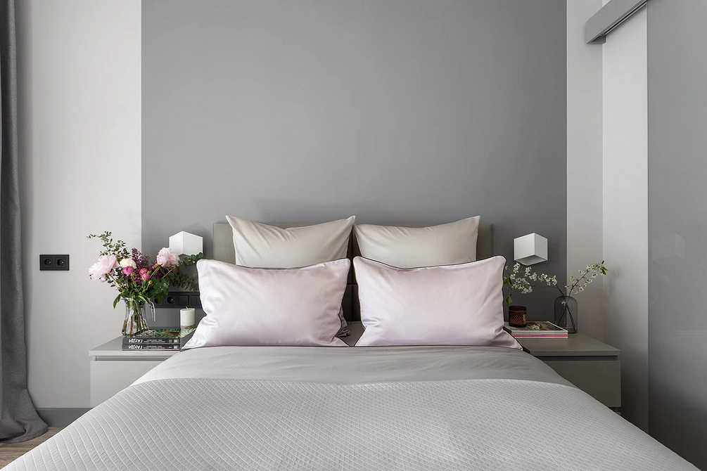 Сучасна сіра спальня з акцентною стіною за ліжком та мінімалістичним дизайном.