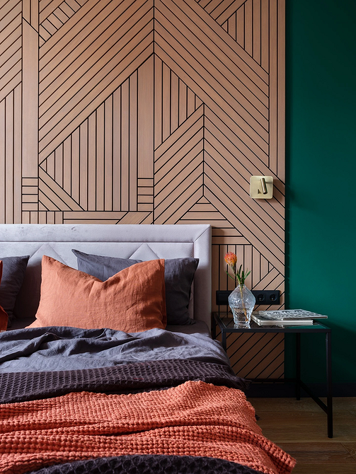 Інтер'єр спальні з сірим ліжком, картинами на стінах та декоративними подушками.