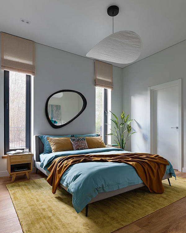 Дизайн спальні з сірим ліжком та акцентною стіною з геометричним малюнком.