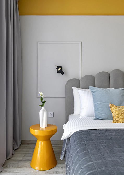 Спальня в стилі мінімалізм з сірим ліжком, білими стінами та лаконічним декором.