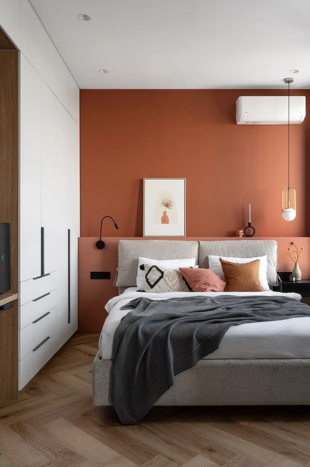 Сучасна спальня з сірим ліжком, мінімалістичним дизайном та великою кількістю подушок.