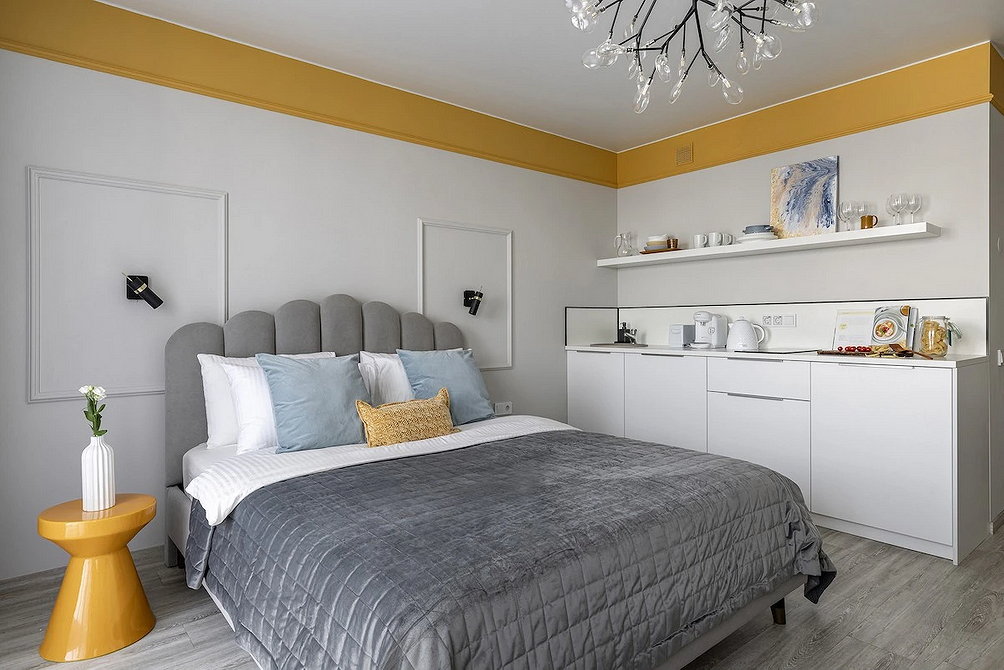 Інтер'єр спальні з сірим ліжком, дерев'яними тумбочками та стильною лампою.