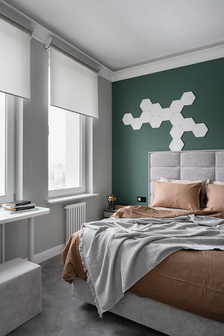 Інтер'єр спальні з сірим ліжком, килимом та декоративними елементами в тон.