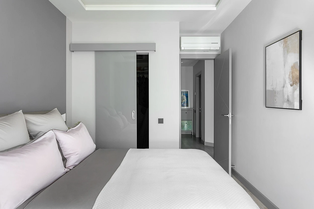 Простора спальня в сірих тонах з великим ліжком та акцентним текстилем.