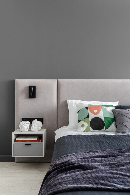 Невелика сіра ліжко в компактній спальні з мінімальною кількістю меблів.