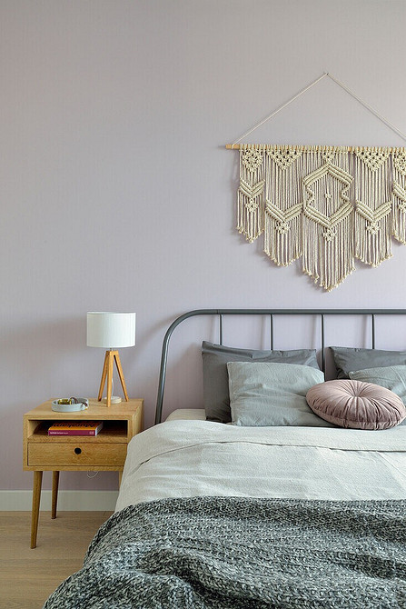 Сучасна сіра ліжко з високим узголів'ям в просторій спальні з великими вікнами.