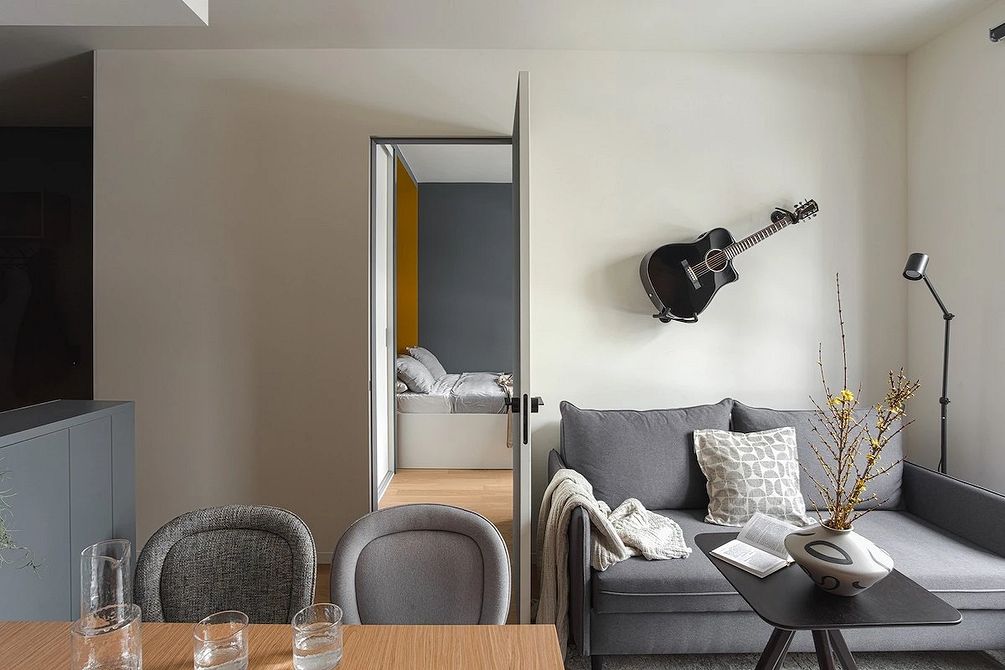 Інтер'єр вітальні з сірим диваном та яскравими кольоровими акцентами в декорі