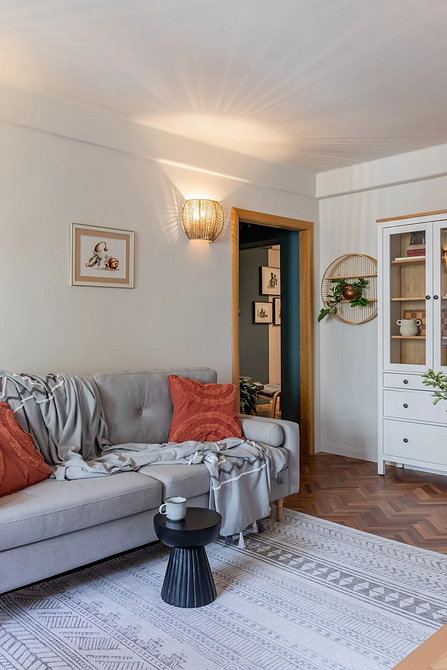 Дизайн вітальні з сірим диваном та декоративними подушками в інтер'єрі.