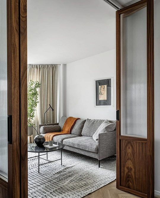 Стильний кутовий сірий диван у вітальні з дерев'яною підлогою та сучасними меблями.