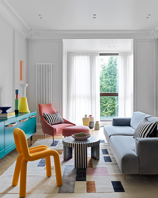 Вітальня з великим сірим диваном, журнальним столиком та книжковою полицею.