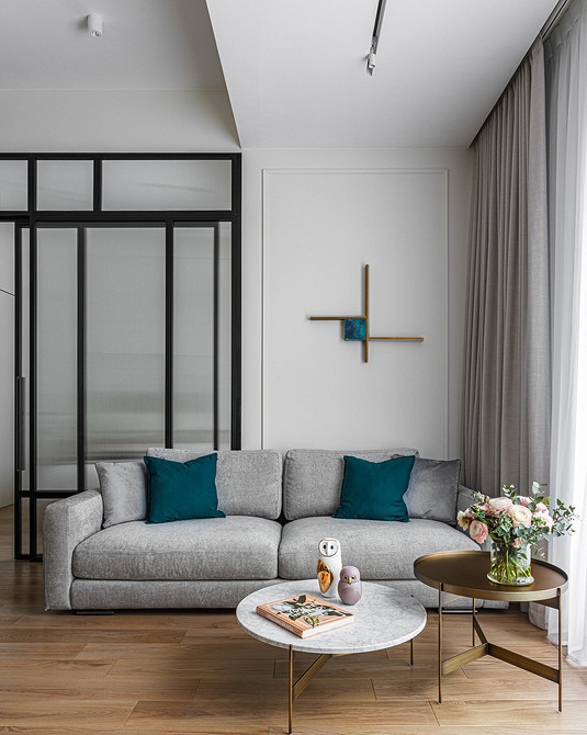 Мінімалістичний інтер'єр з сірим диваном та чорно-білими фотографіями на стіні