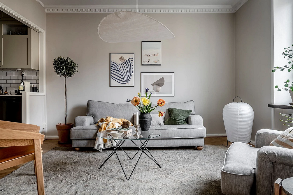 Світлий інтер'єр з сірим диваном, пледом та декоративними подушками для затишку