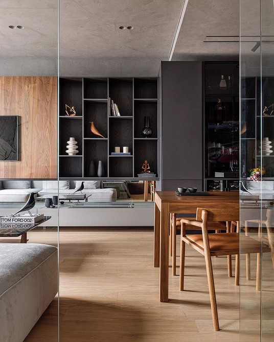 Чорна тумба під телевізор з глянцевими фасадами в мінімалістичній вітальні.