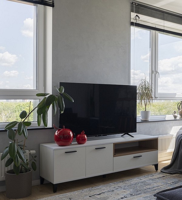 Дизайн вітальні з низькою тумбою під телевізор для зручного перегляду та зберігання речей.