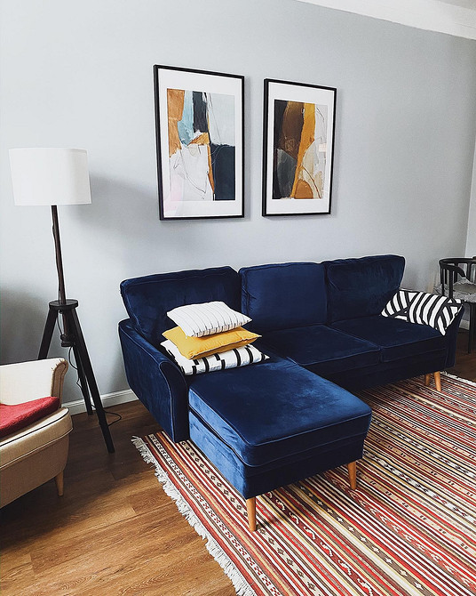 Інтер'єр з синім диваном, декоративними подушками та картиною на стіні