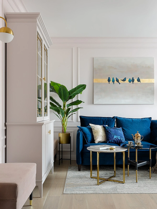 Синій диван в сучасному інтер'єрі вітальні з яскравими акцентами та кольоровими подушками.