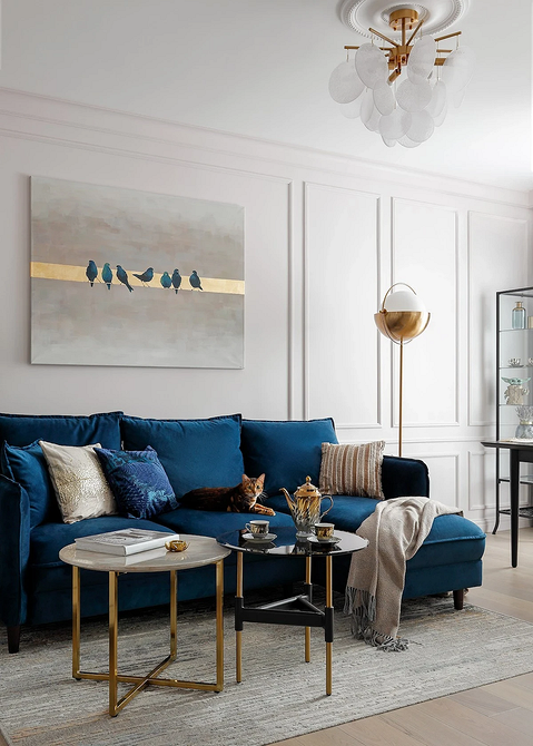 Розкішний синій велюровий диван у вітальні з елегантним дизайном та стильним декором.