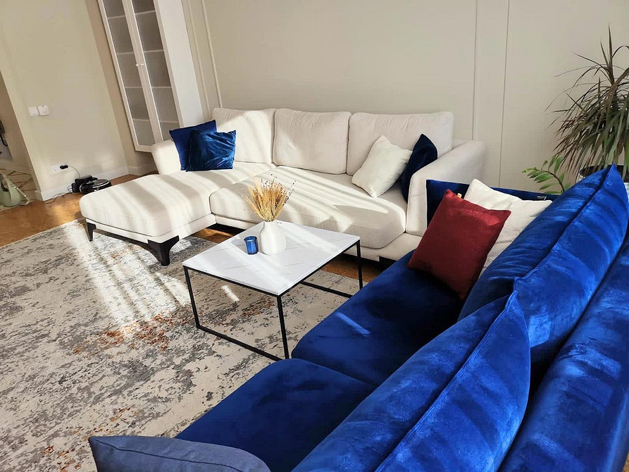 Дизайн вітальні з синім диваном, дерев'яною стіною та абстрактною картиною.