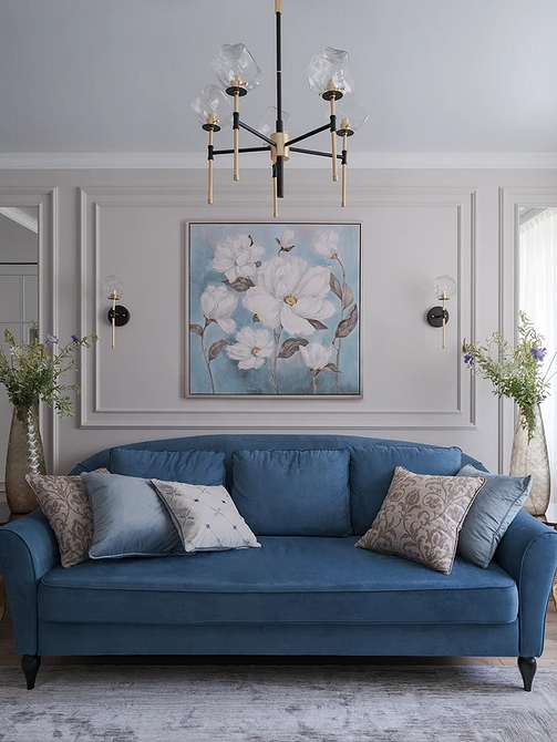 Інтер'єр з синім диваном, книжковою полицею та декоративним каміном у вітальні.