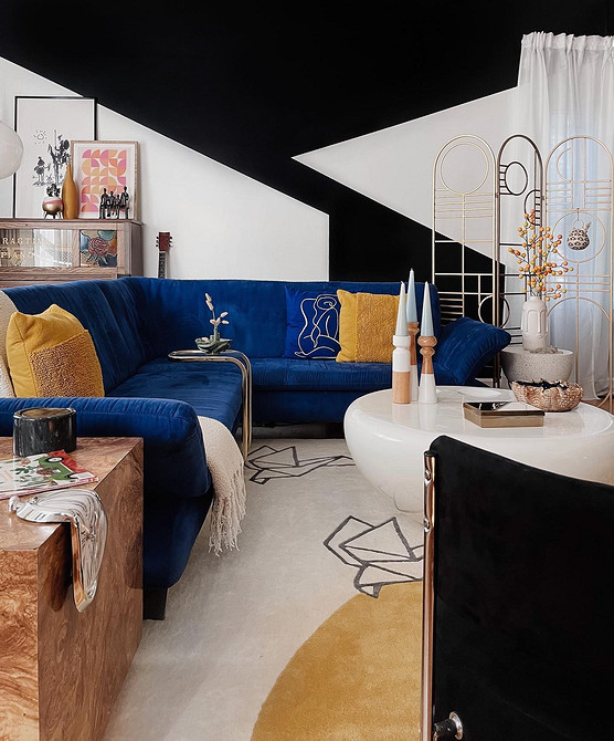 Інтер'єр з синім диваном, жовтими акцентами та рослинами в горщиках.