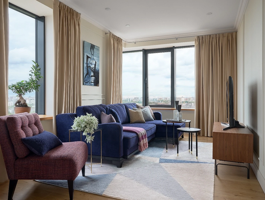 Поєднання синього дивана з жовтими подушками та картинами в інтер'єрі