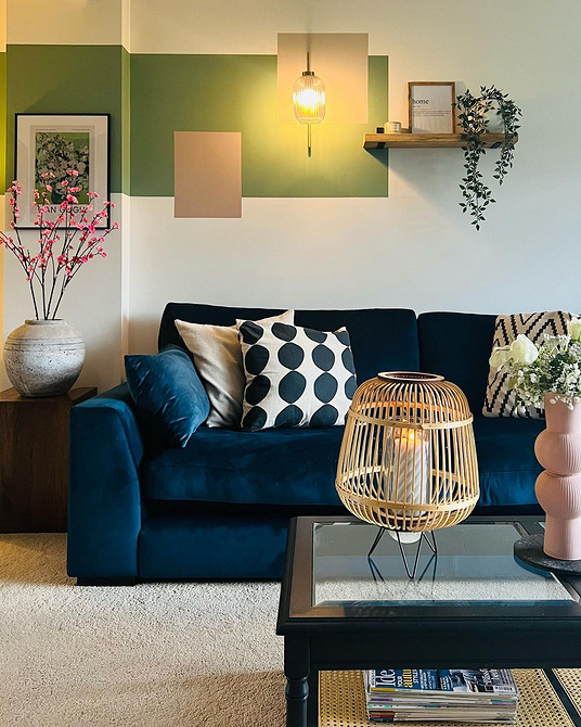 Дизайн вітальні з яскраво-синім диваном та чорно-білими фотографіями на стіні.