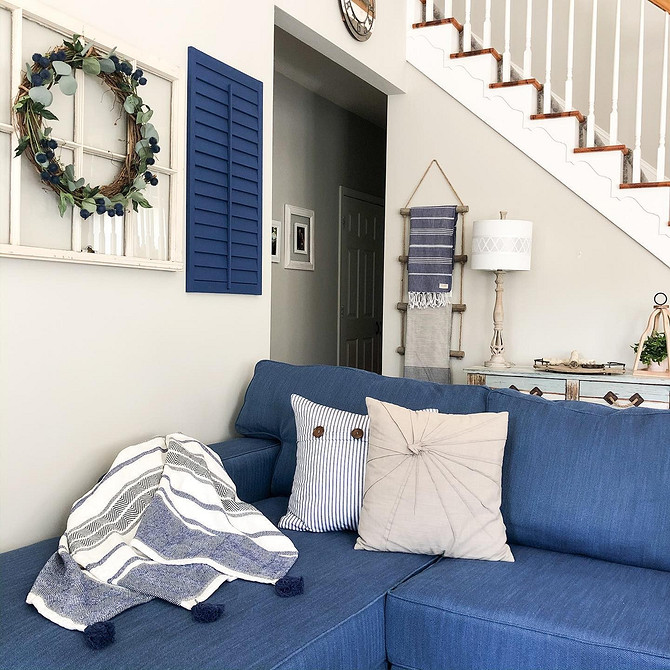 Синій диван в інтер'єрі з бежевими стінами, килимом та дерев'яними меблями