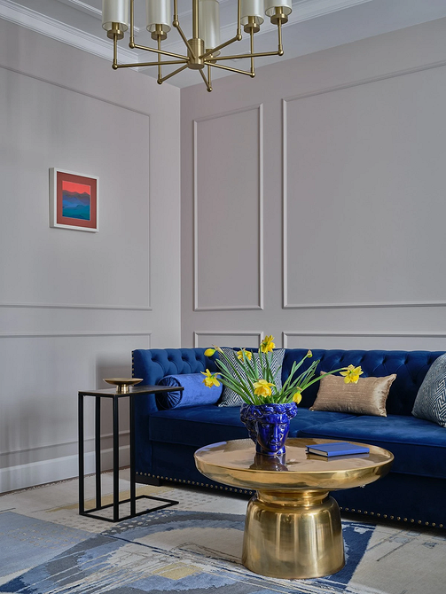 Вітальня з синім кутовим диваном, дерев'яним столиком та зеленими рослинами.