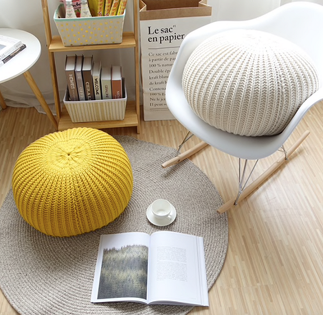 Пуф з м'якою оббивкою та стильне крісло в сучасному інтер'єрі кімнати.