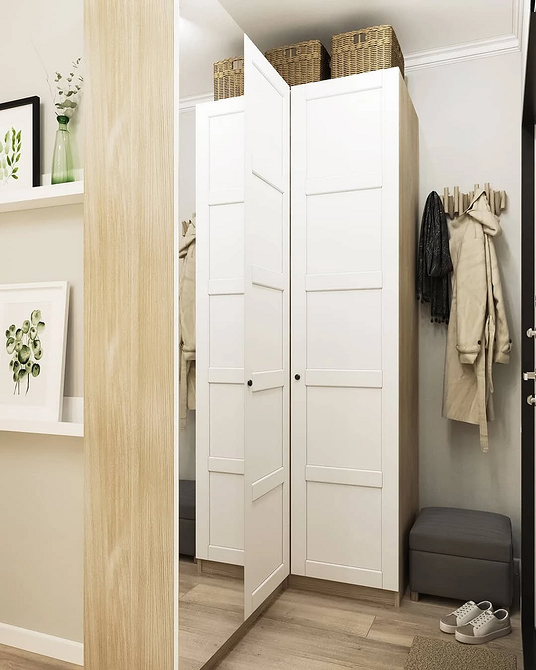 Кутова шафа з дзеркальними дверцятами у невеликій кімнаті, ергономічне рішення для зберігання.