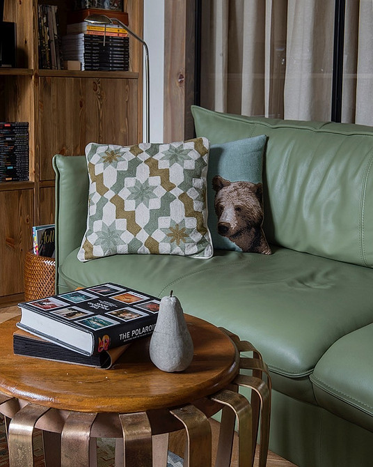 Інтер'єр вітальні з зеленим диваном, шторами та декоративними елементами