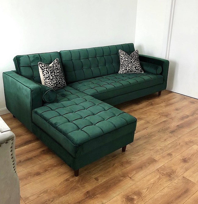 Світло-зелений диван у вітальні з великою кількістю природного світла та білими стінами.