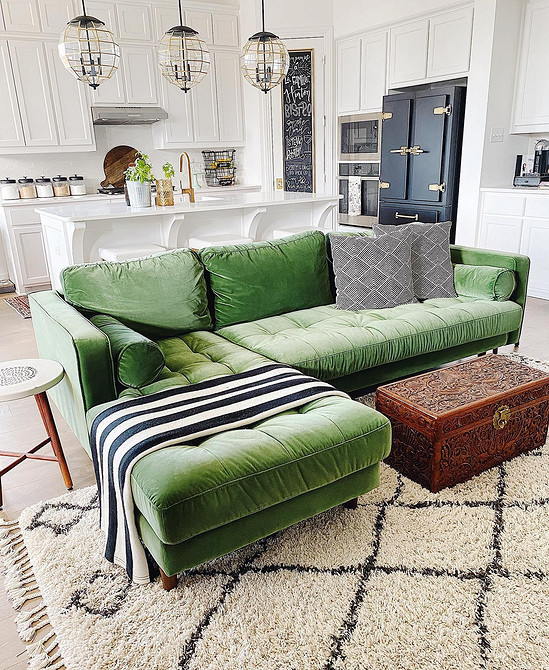 Інтер'єр з великим зеленим диваном, текстилем для дому та декоративними елементами