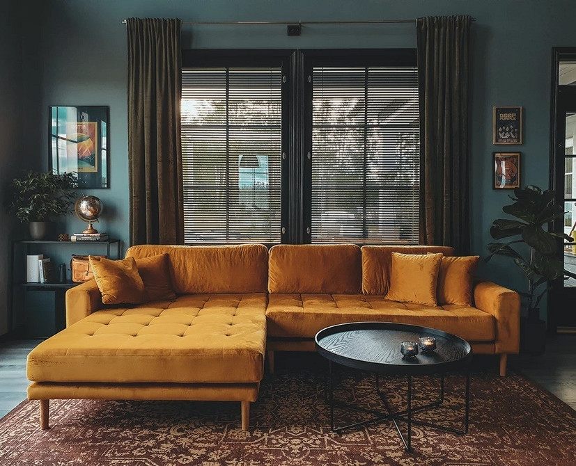 Невеликий жовтий диван в інтер'єрі маленької вітальні з яскравими акцентами.