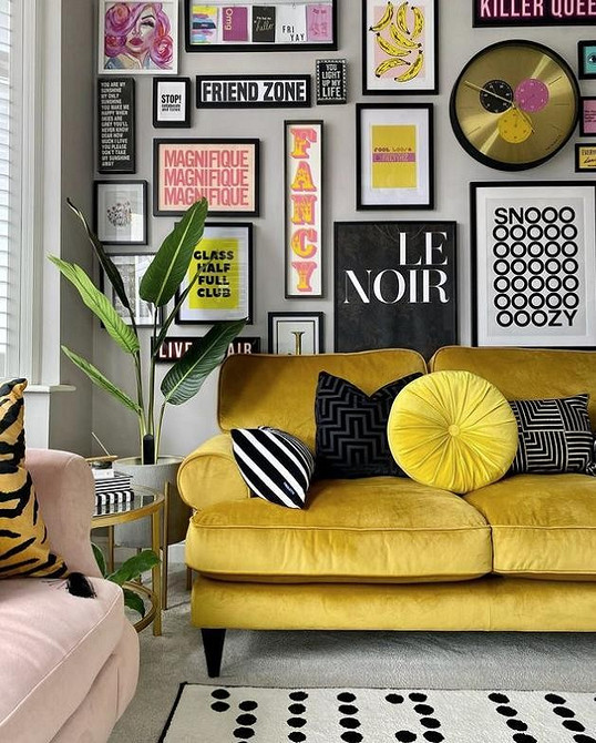 Жовтий кутовий диван у просторій вітальні з великими вікнами та килимом на підлозі.