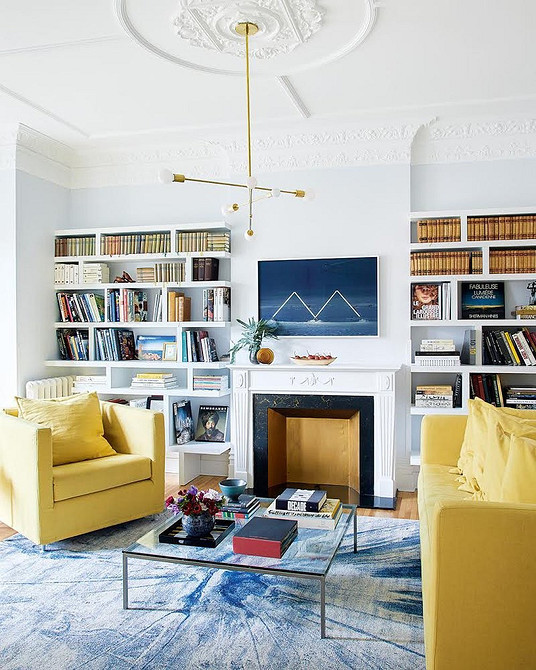 Жовтий диван в інтер'єрі з великим вікном, що виходить у сад.