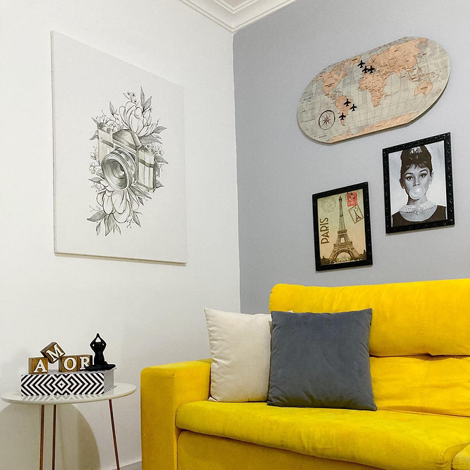 Інтер'єр з жовтим диваном, дерев'яним столиком і декоративними подушками, що створюють затишок.