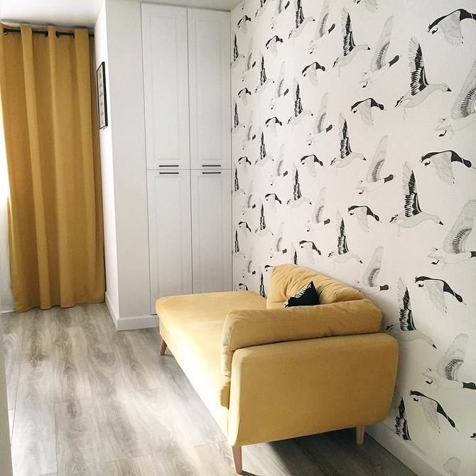 Жовтий диван в мінімалістичному інтер'єрі з білими стінами та яскравими акцентами декору.