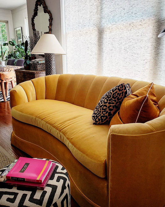 Жовтий диван з різнокольоровими подушками в сучасному інтер'єрі з дерев'яною підлогою.